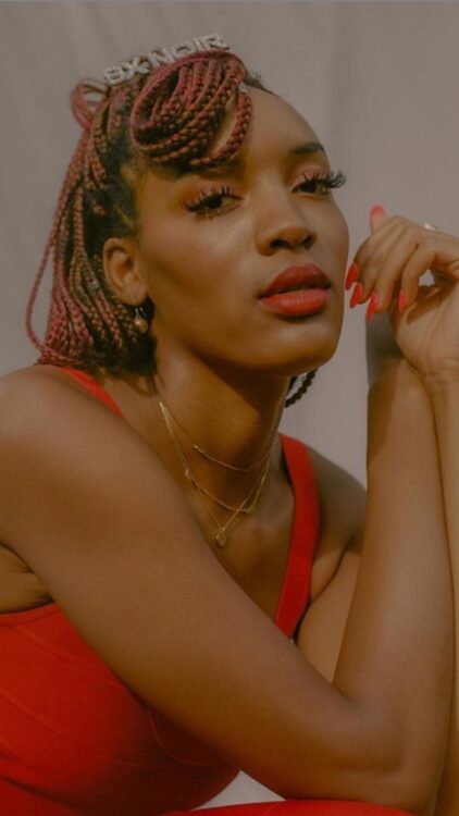 sex work activist and "thot leader" SX Noir poses with red braids and a red tank top